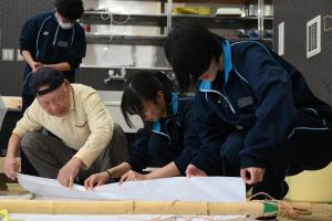 和紙の貼り付けを行う高校生と協会の人