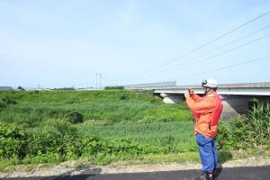 河川の現場から情報を送る消防団員
