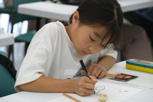 集中してお父さんの似顔絵を描いている児童