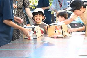 手作りペットボトルカーを走らせるこども